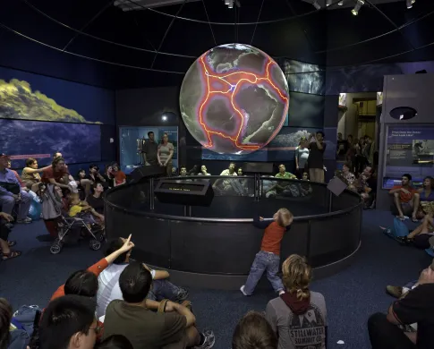 Photo of visitors sitting around a giant suspended globe of planet earth