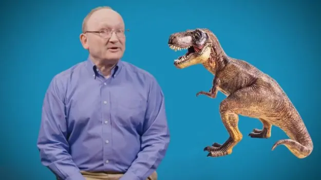 Dr. Hans Sues in front of a blue screen next to a dinosaur. 