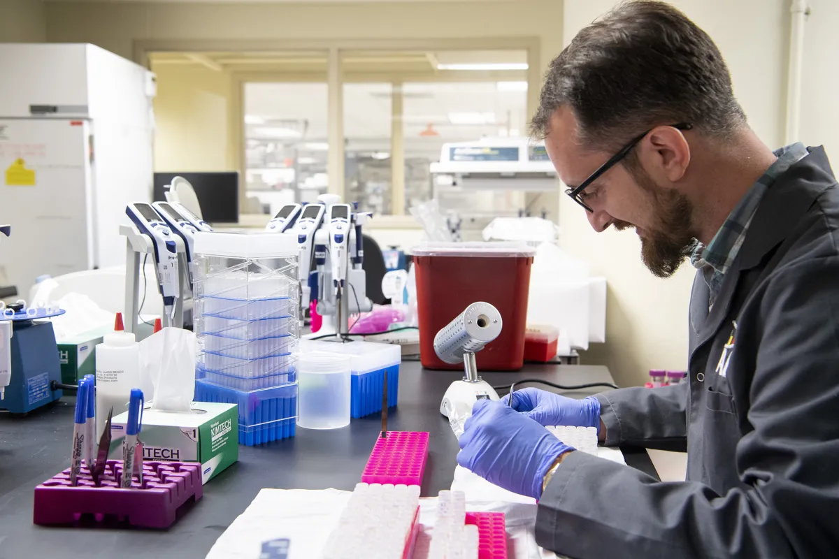 A scientist sits in a lab with equipment. 